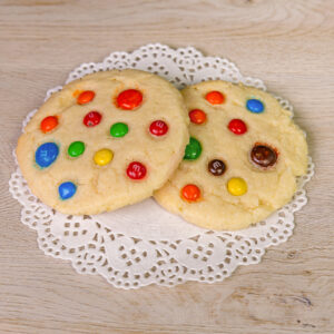 Two cookies with colorful candies on a doily.