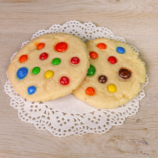Two cookies with colorful candies on a doily.
