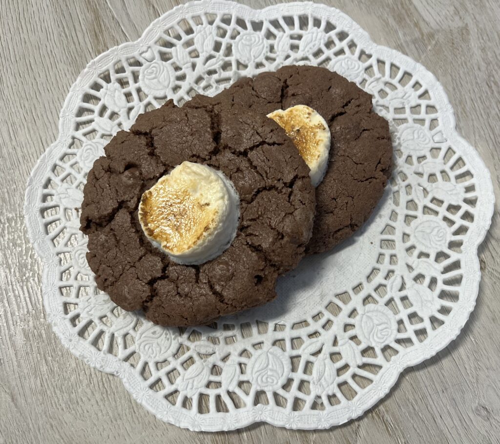 Chocolate cookies with marshmallows on lace doily.